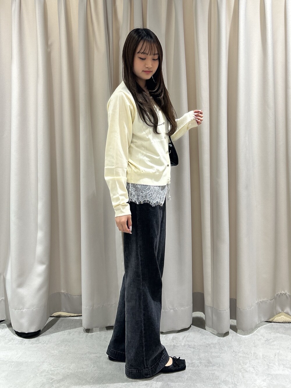 ホワイト系のニット/セーター、ブラック系のデニムパンツ、ブラック系のショルダーバッグを着用したレディースの夏コーディネートの3枚目の写真