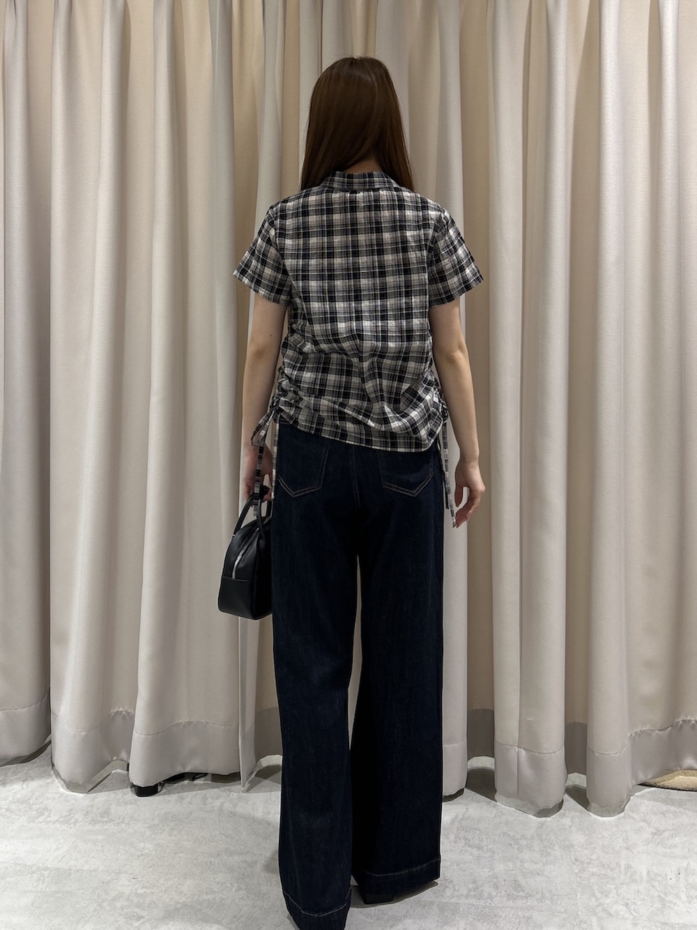 ブルー系のデニムパンツ、ブラック系のシャツ/ブラウス、ブラック系のハンドバッグを着用したレディースの夏コーディネートの4枚目の写真