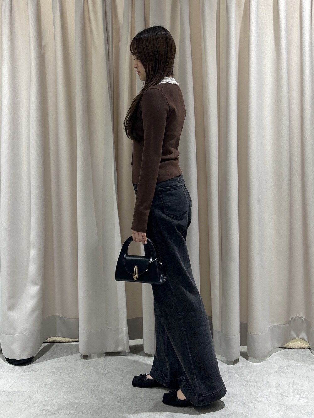 ブラウン系のニット/セーター、ブラック系のデニムパンツ、ブラック系のショルダーバッグを着用したレディースの秋コーディネートの2枚目の写真