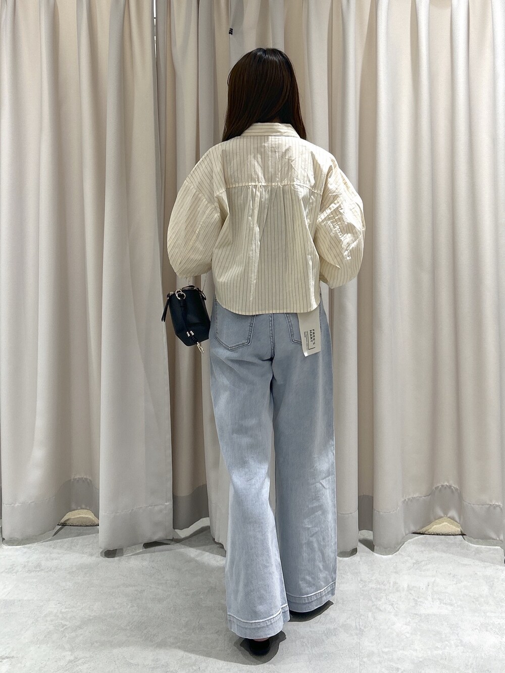 ホワイト系のシャツ/ブラウス、ブラック系のショルダーバッグ、ブルー系のデニムパンツを着用したレディースの秋コーディネートの3枚目の写真