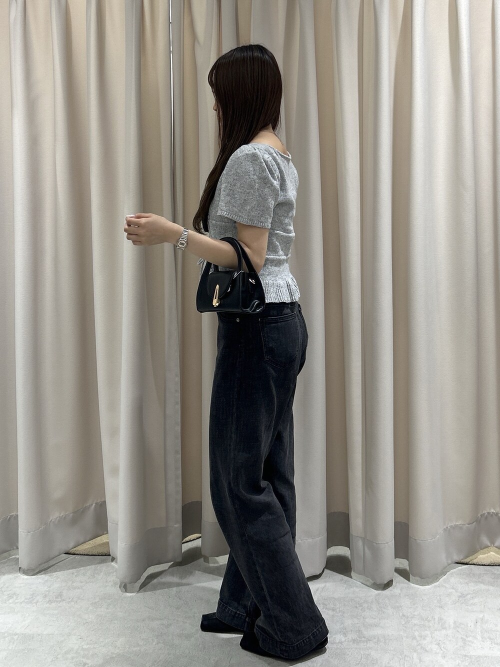 グレー系のニット/セーター、ブラック系のデニムパンツ、ブラック系のショルダーバッグを着用したレディースの夏コーディネートの3枚目の写真