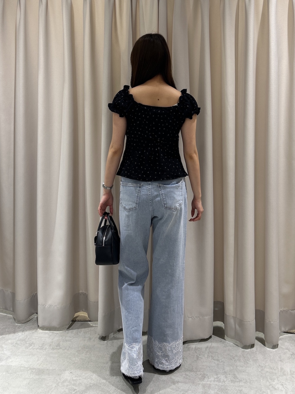 ブルー系のデニムパンツ、ブラック系のTシャツ/カットソー、ブラック系のハンドバッグを着用したレディースの夏コーディネートの4枚目の写真