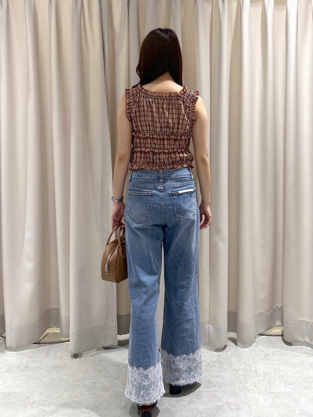 レッド系のシャツ/ブラウス、ブルー系のデニムパンツ、ブラウン系のハンドバッグを着用したレディースの夏コーディネートの3枚目の写真