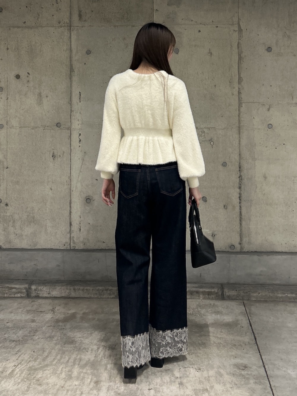 ホワイト系のニット/セーター、ブルー系のデニムパンツ、ブラック系のショルダーバッグを着用したレディースの秋コーディネートの3枚目の写真