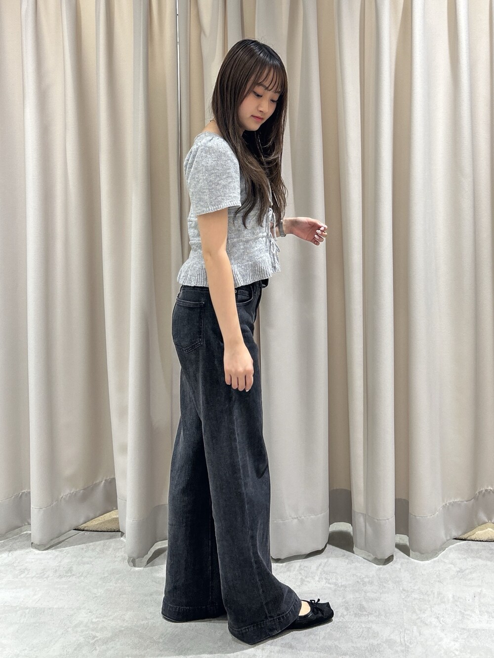 グレー系のニット/セーター、ブラック系のデニムパンツ、ブラック系のショルダーバッグを着用したレディースの夏コーディネートの2枚目の写真