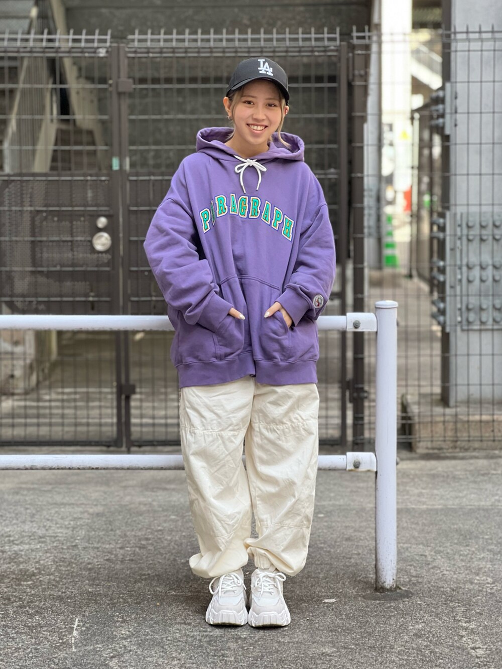 パープル系のパーカー、ホワイト系のチノパンツ、ホワイト系のスニーカーを着用したレディースの春コーディネートの2枚目の写真