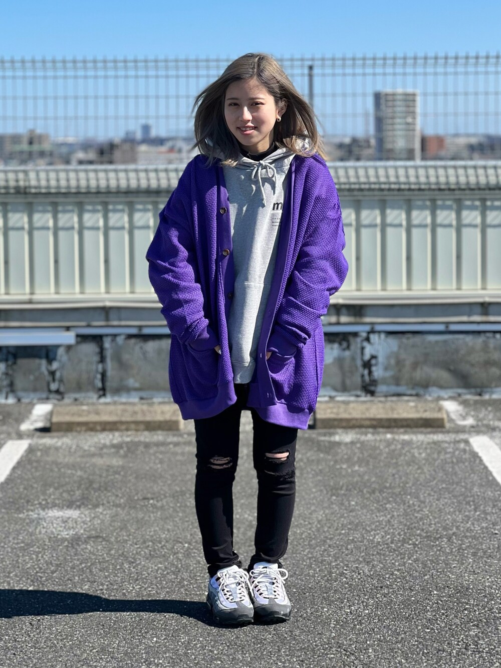 パープル系のカーディガン/ボレロ、グレー系のパーカー、ブラック系のデニムパンツを着用したレディースの春コーディネートの2枚目の写真