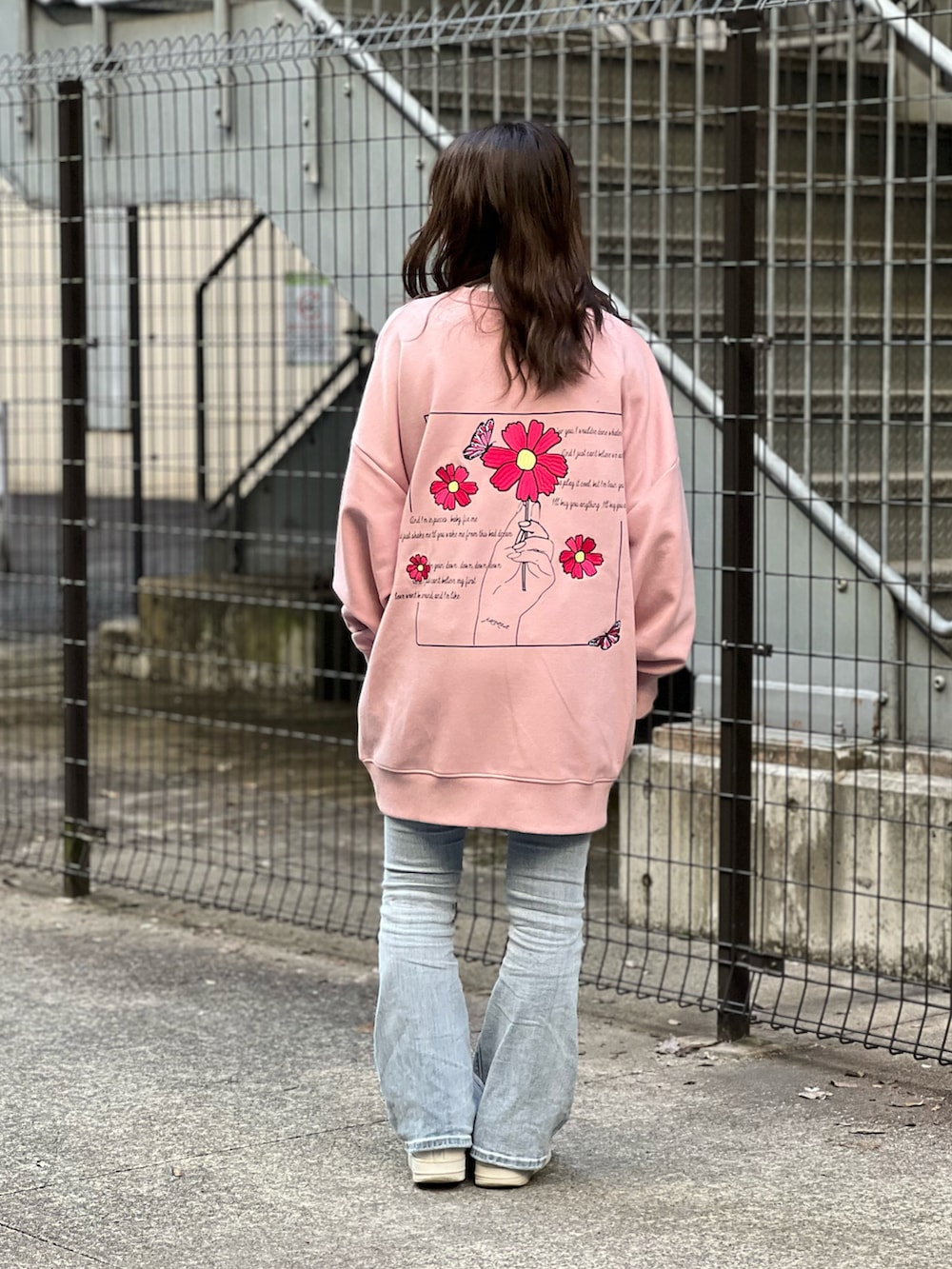 ピンク系のスウェット、ブルー系のデニムパンツを着用したレディースの冬コーディネートの2枚目の写真