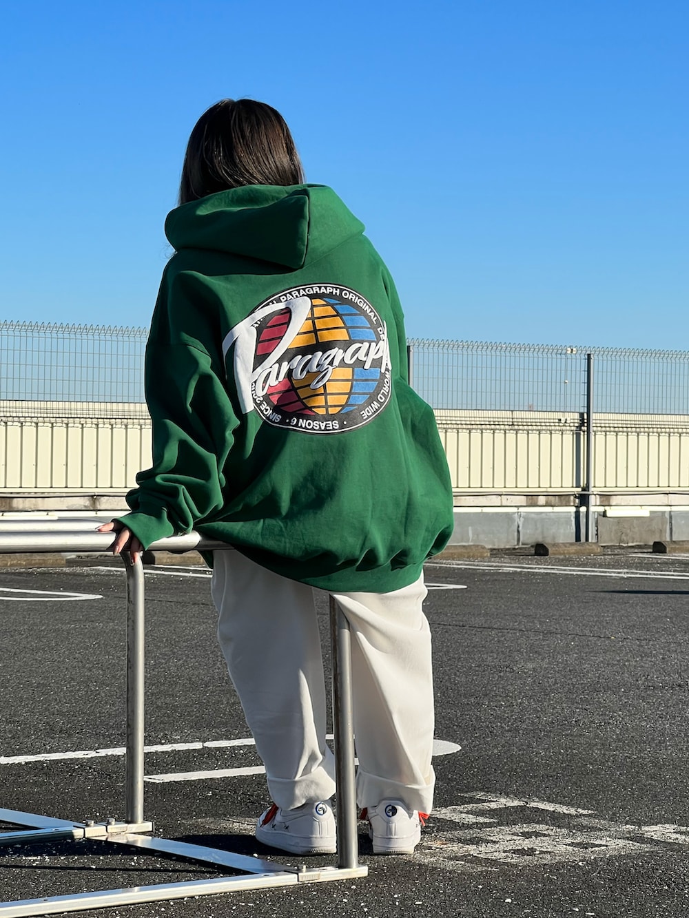 グリーン系のパーカー、ホワイト系のチノパンツを着用したレディースの冬コーディネートの2枚目の写真