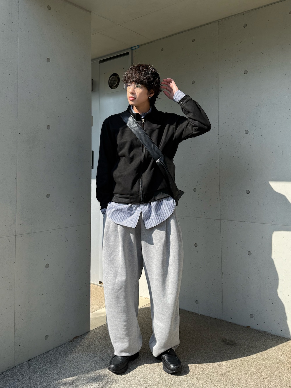 グレー系のスウェットパンツ、ブラック系のスニーカー、ブラック系のその他アウターを着用したメンズの春コーディネートの2枚目の写真