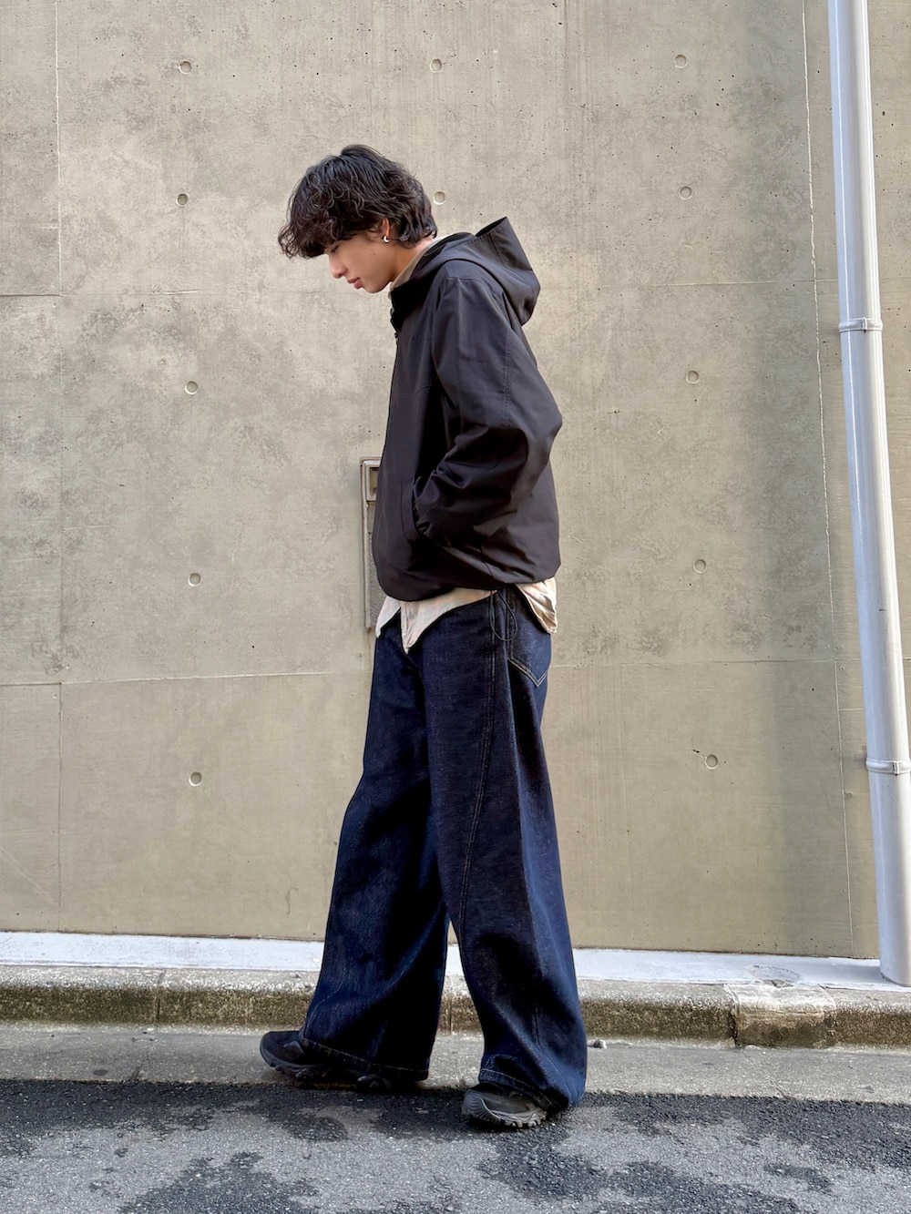 ブルー系のデニムパンツ、ブラック系のスニーカー、ブラック系のマウンテンパーカーを着用したメンズの春コーディネートの2枚目の写真