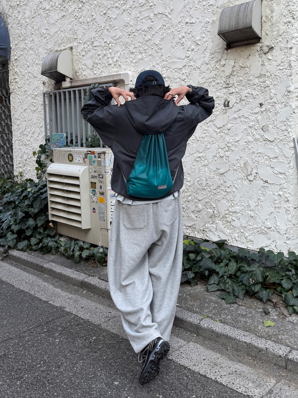 グレー系のマウンテンパーカー、ブラック系のスニーカー、グレー系のスウェットパンツを着用したメンズの春コーディネートの2枚目の写真