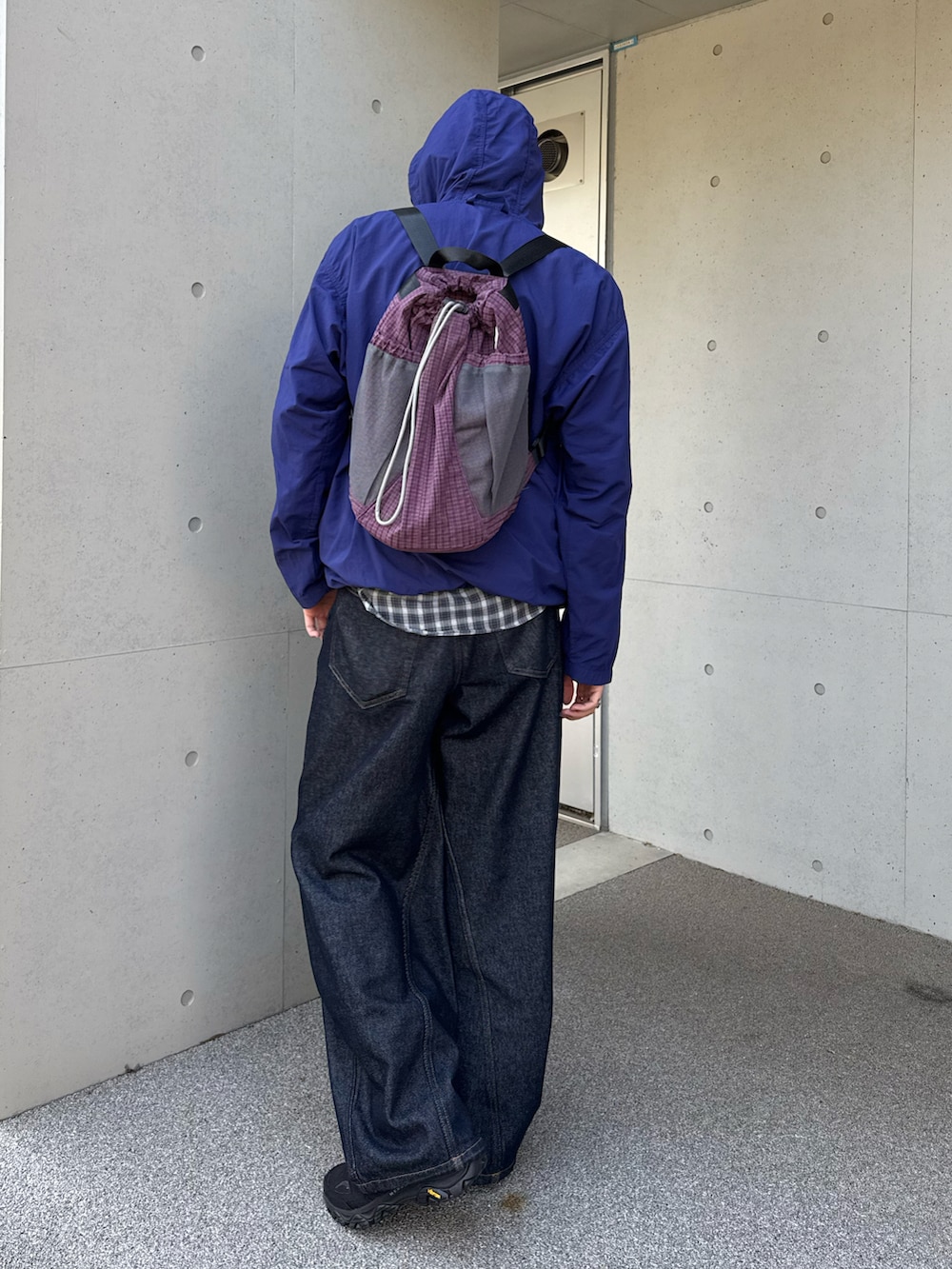 パープル系のナイロンジャケット、ブルー系のデニムパンツ、ブラック系のスニーカーを着用したメンズの春コーディネートの2枚目の写真