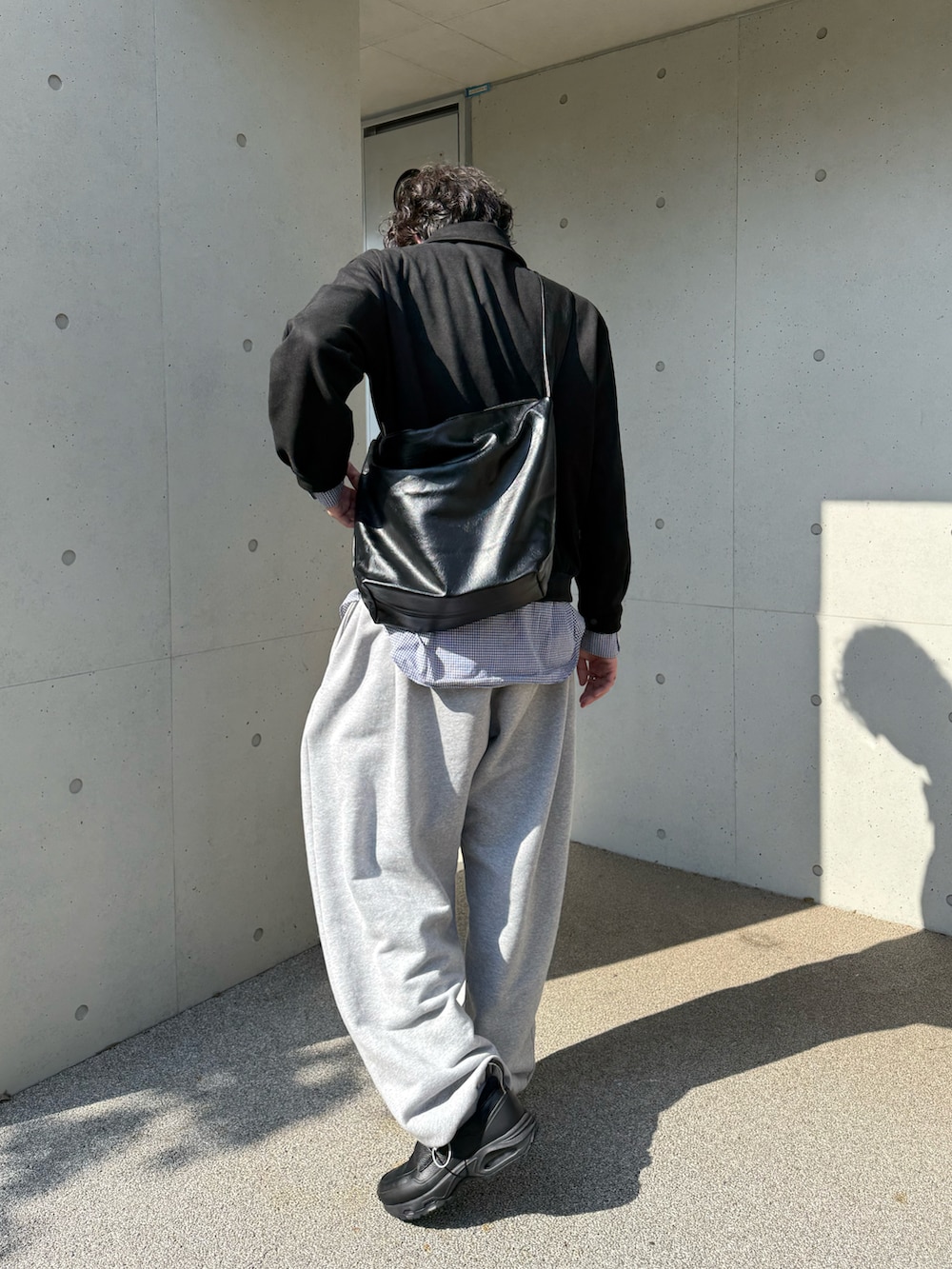 グレー系のスウェットパンツ、ブラック系のスニーカー、ブラック系のその他アウターを着用したメンズの春コーディネートの3枚目の写真