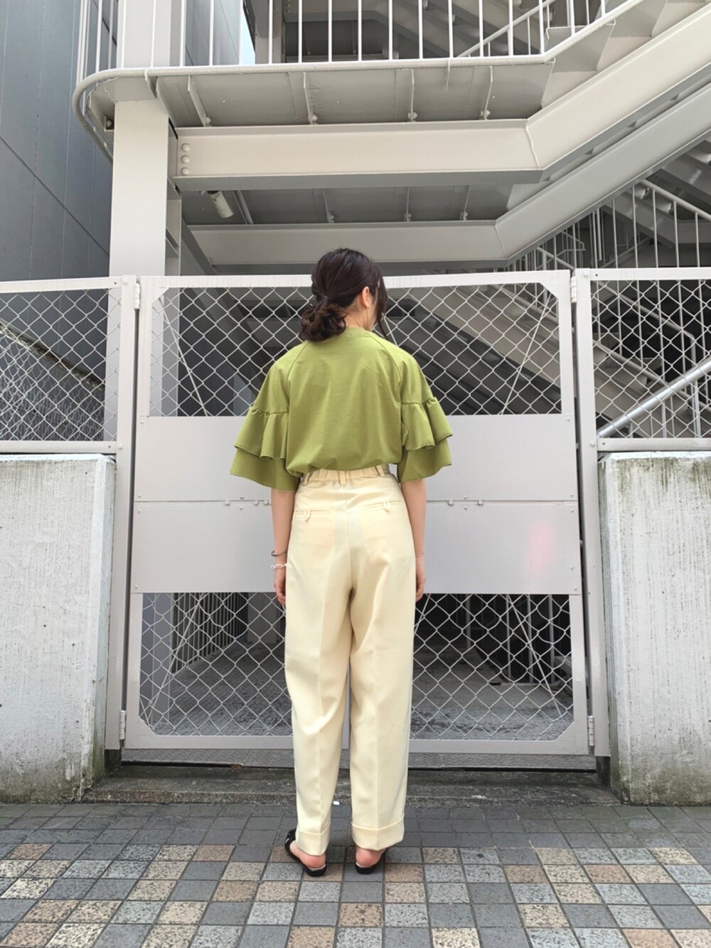 グリーン系のTシャツ/カットソー、ホワイト系のその他パンツ、ブラック系のサンダルを着用したレディースの春コーディネートの2枚目の写真