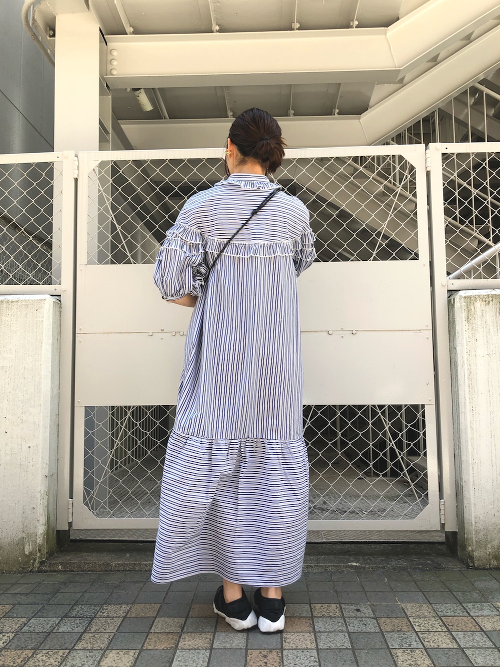 ブルー系のワンピース、ブラック系のショルダーバッグ、ゴールド系のブレスレットを着用したレディースの春コーディネートの2枚目の写真