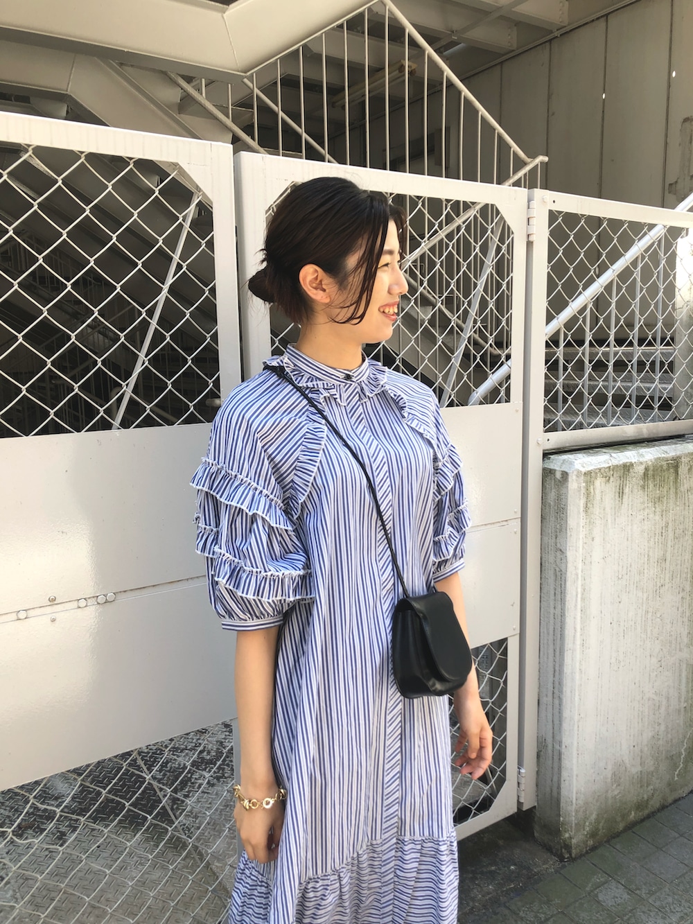 ブルー系のワンピース、ブラック系のショルダーバッグ、ゴールド系のブレスレットを着用したレディースの春コーディネートの4枚目の写真