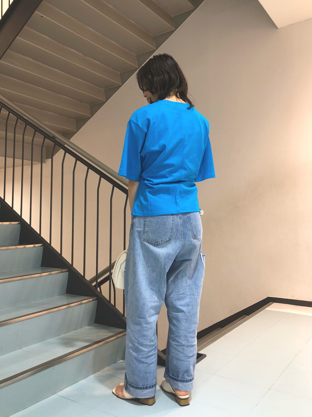 ブルー系のTシャツ/カットソー、ブルー系のデニムパンツ、ホワイト系のボストンバッグを着用したレディースの夏コーディネートの2枚目の写真