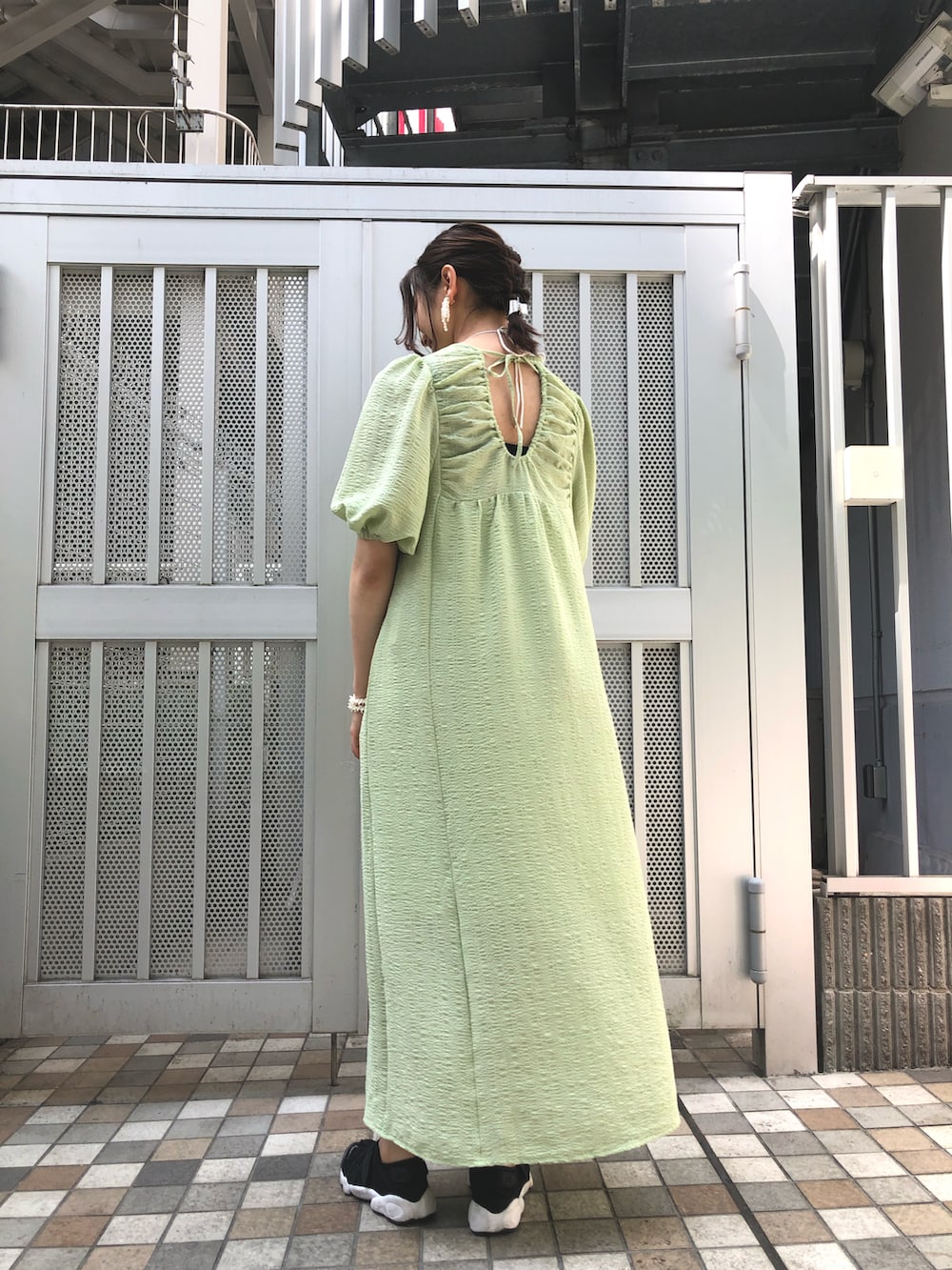 グリーン系のワンピース、グレー系のニット/セーター、ホワイト系のイヤリングを着用したレディースの春コーディネートの2枚目の写真