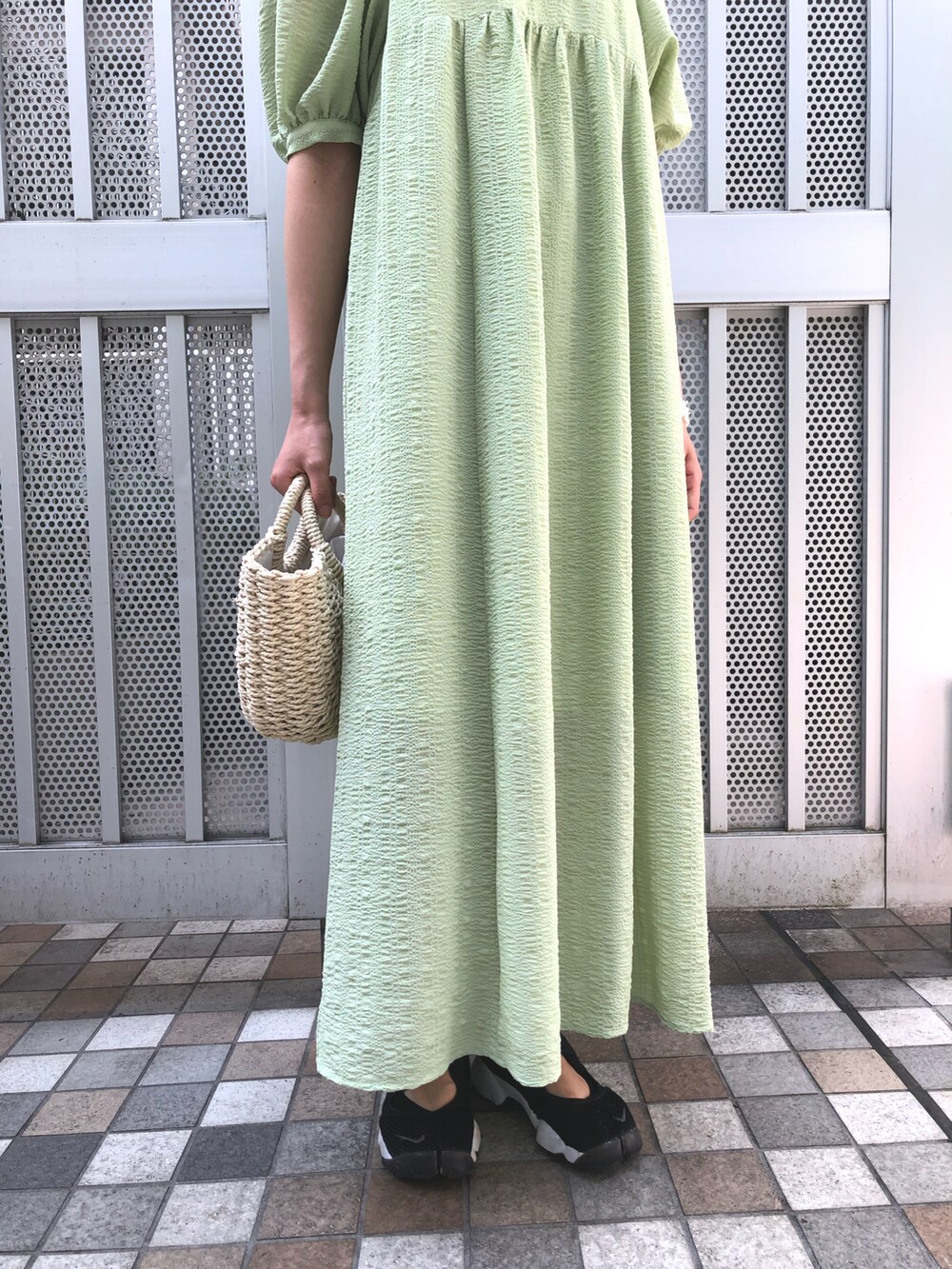 グリーン系のワンピース、グレー系のニット/セーター、ホワイト系のイヤリングを着用したレディースの春コーディネートの5枚目の写真