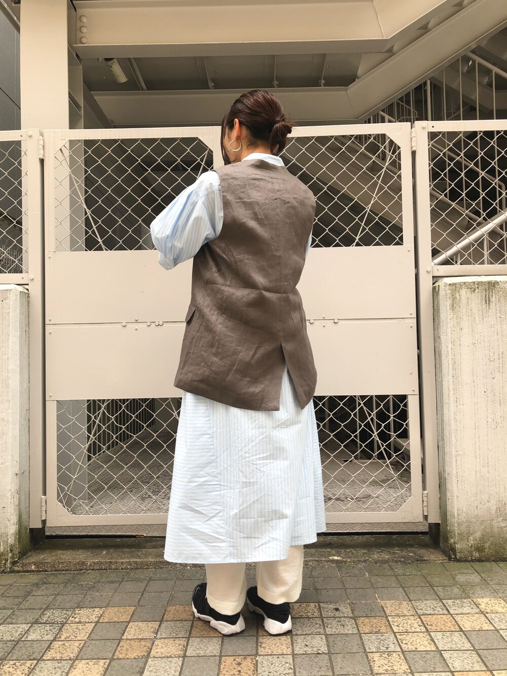 ブルー系のワンピース、ベージュ系のベスト、ホワイト系のその他パンツを着用したレディースの春コーディネートの2枚目の写真