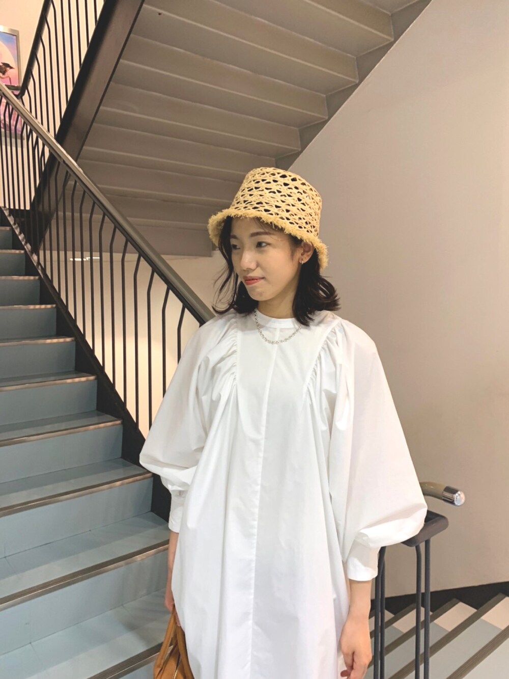 ホワイト系のワンピース、イエロー系のボストンバッグ、ベージュ系のハットを着用したレディースの春コーディネートの3枚目の写真