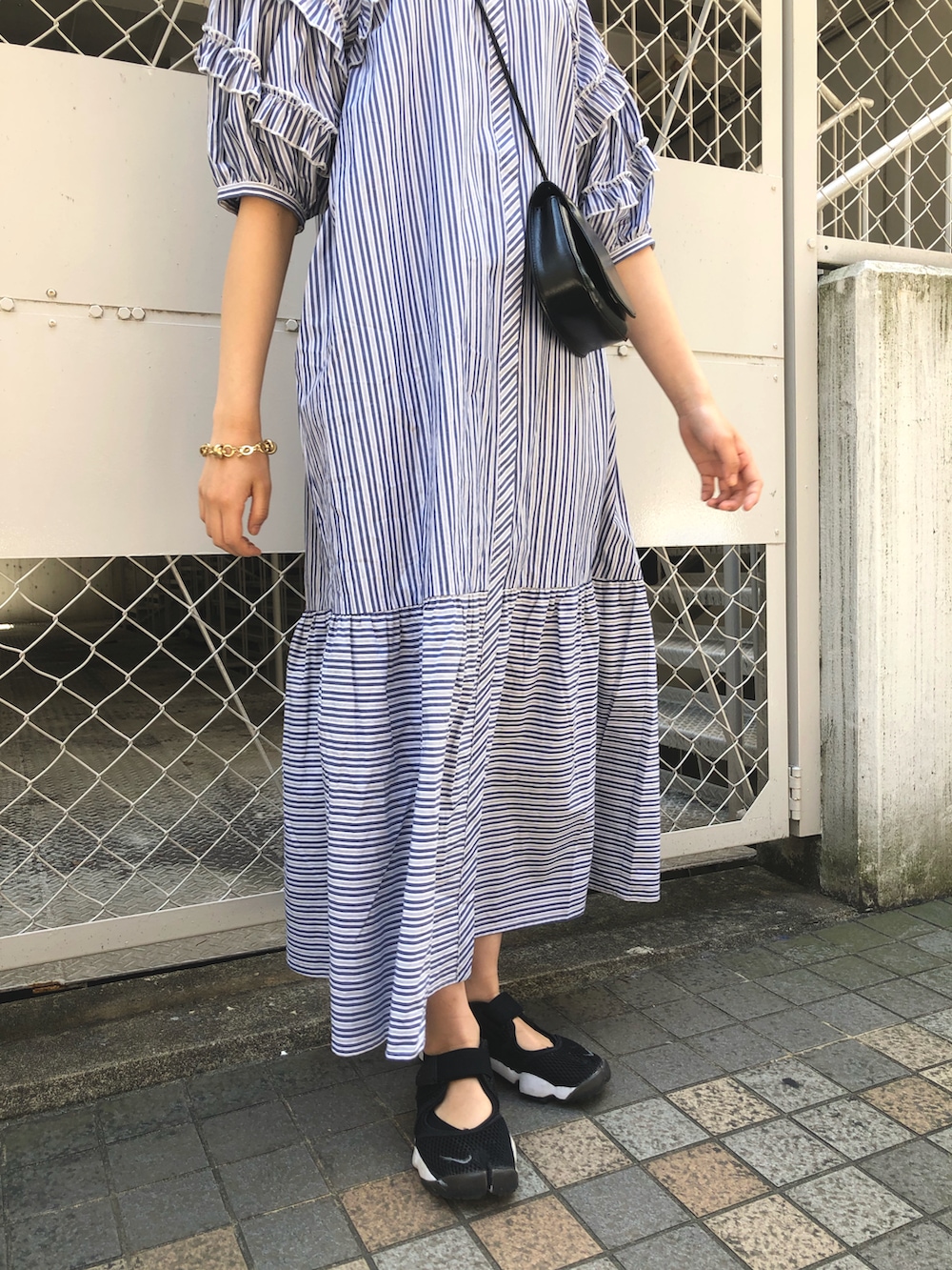 ブルー系のワンピース、ブラック系のショルダーバッグ、ゴールド系のブレスレットを着用したレディースの春コーディネートの5枚目の写真