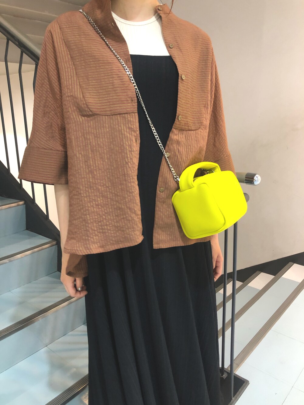 ブラウン系のシャツ/ブラウス、ブラック系のワンピース、イエロー系のハンドバッグを着用したレディースの春コーディネートの4枚目の写真