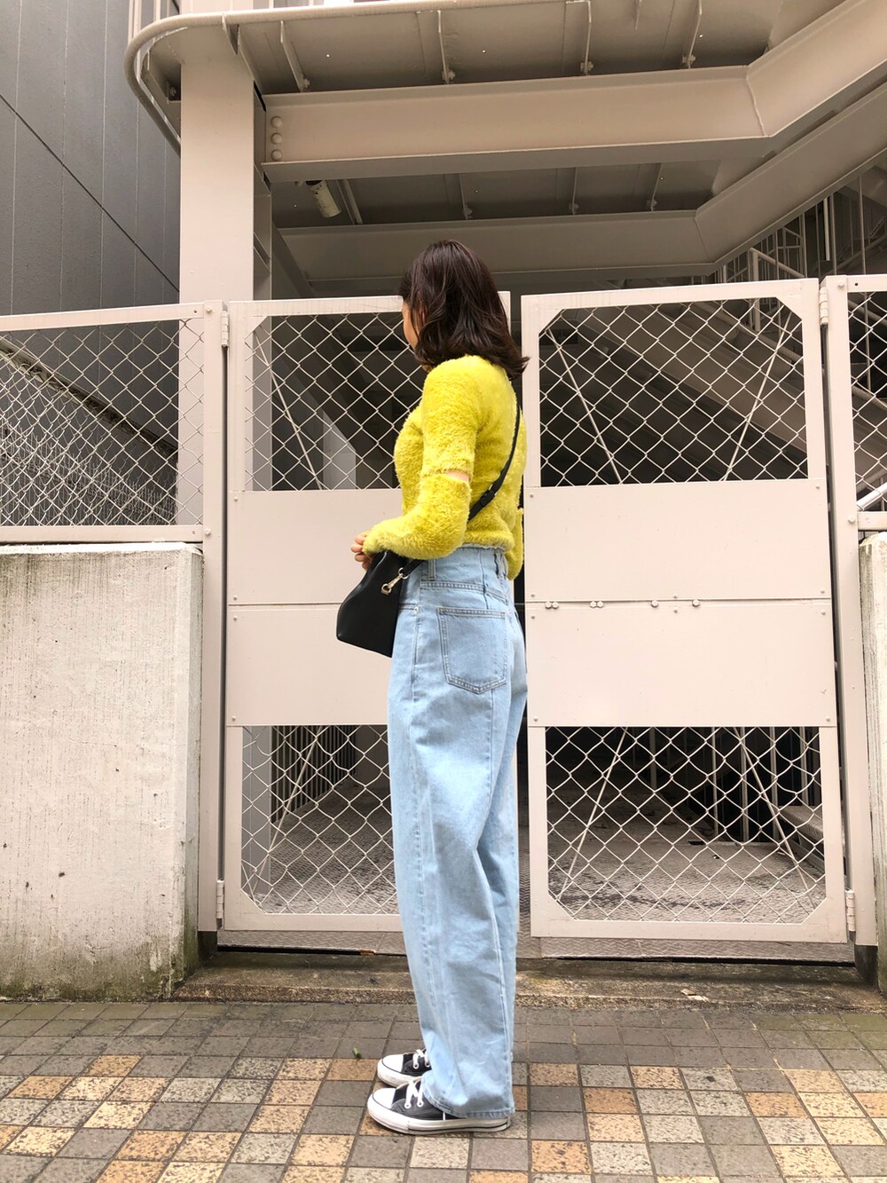 イエロー系のニット/セーター、ブルー系のデニムパンツを着用したレディースの春コーディネートの2枚目の写真