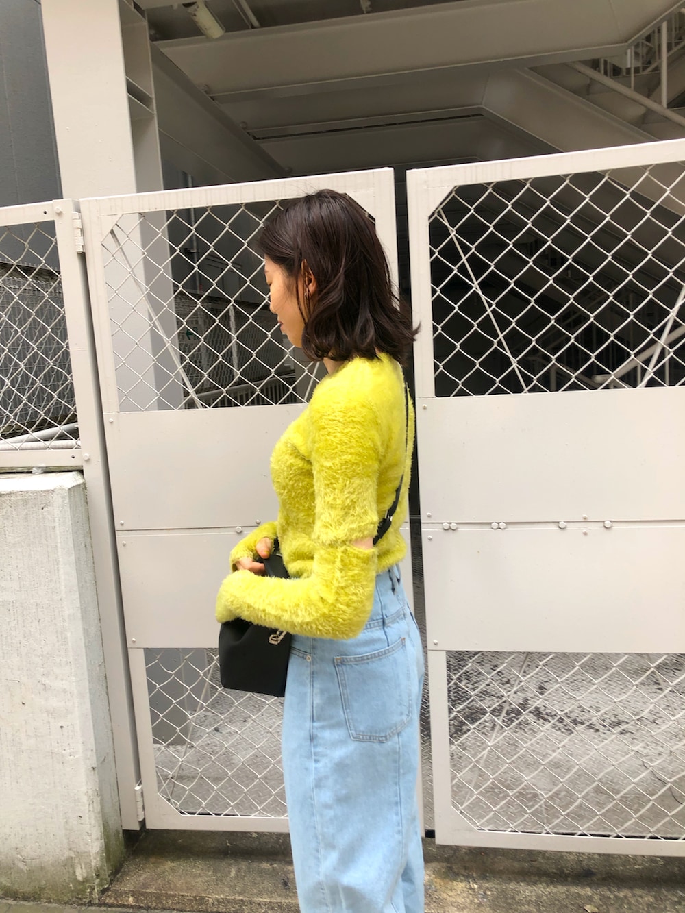 イエロー系のニット/セーター、ブルー系のデニムパンツを着用したレディースの春コーディネートの3枚目の写真