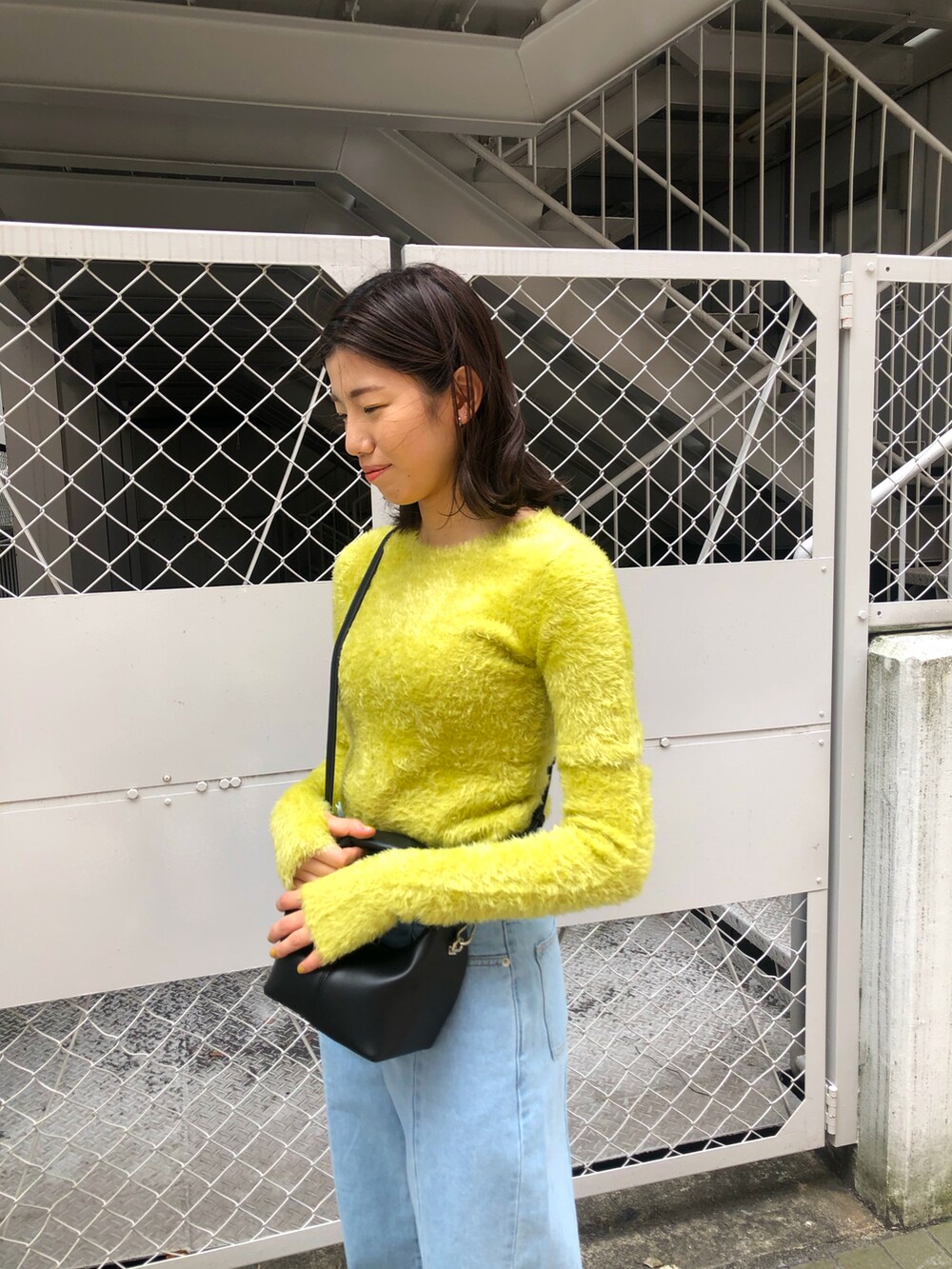 イエロー系のニット/セーター、ブルー系のデニムパンツを着用したレディースの春コーディネートの4枚目の写真