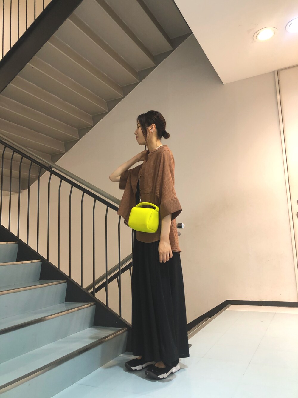 ブラウン系のシャツ/ブラウス、ブラック系のワンピース、イエロー系のハンドバッグを着用したレディースの春コーディネートの3枚目の写真