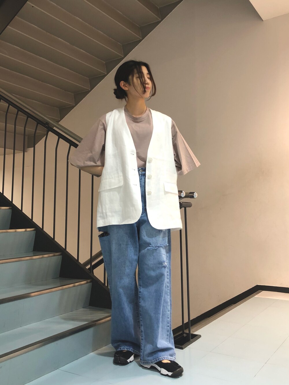 ホワイト系のベスト、ブラック系のTシャツ/カットソー、ブルー系のデニムパンツを着用したレディースの春コーディネートの3枚目の写真