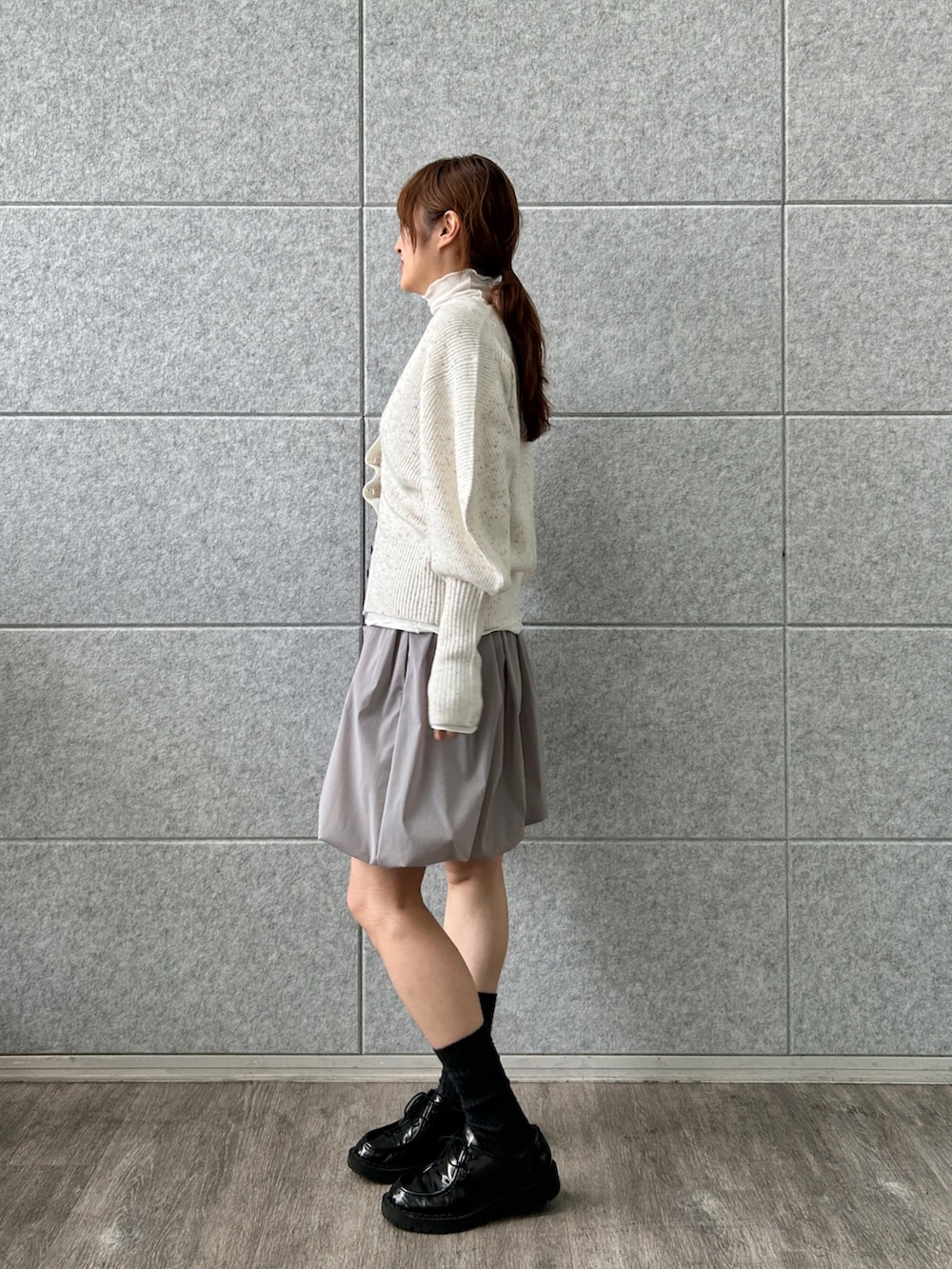 ホワイト系のカーディガン/ボレロ、グレー系のスカート、ホワイト系のTシャツ/カットソーを着用したレディースの冬コーディネートの3枚目の写真