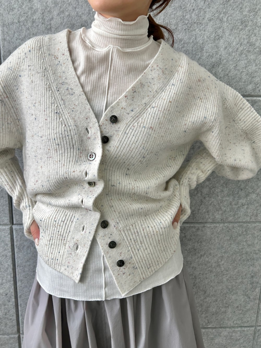 ホワイト系のカーディガン/ボレロ、グレー系のスカート、ホワイト系のTシャツ/カットソーを着用したレディースの冬コーディネートの5枚目の写真