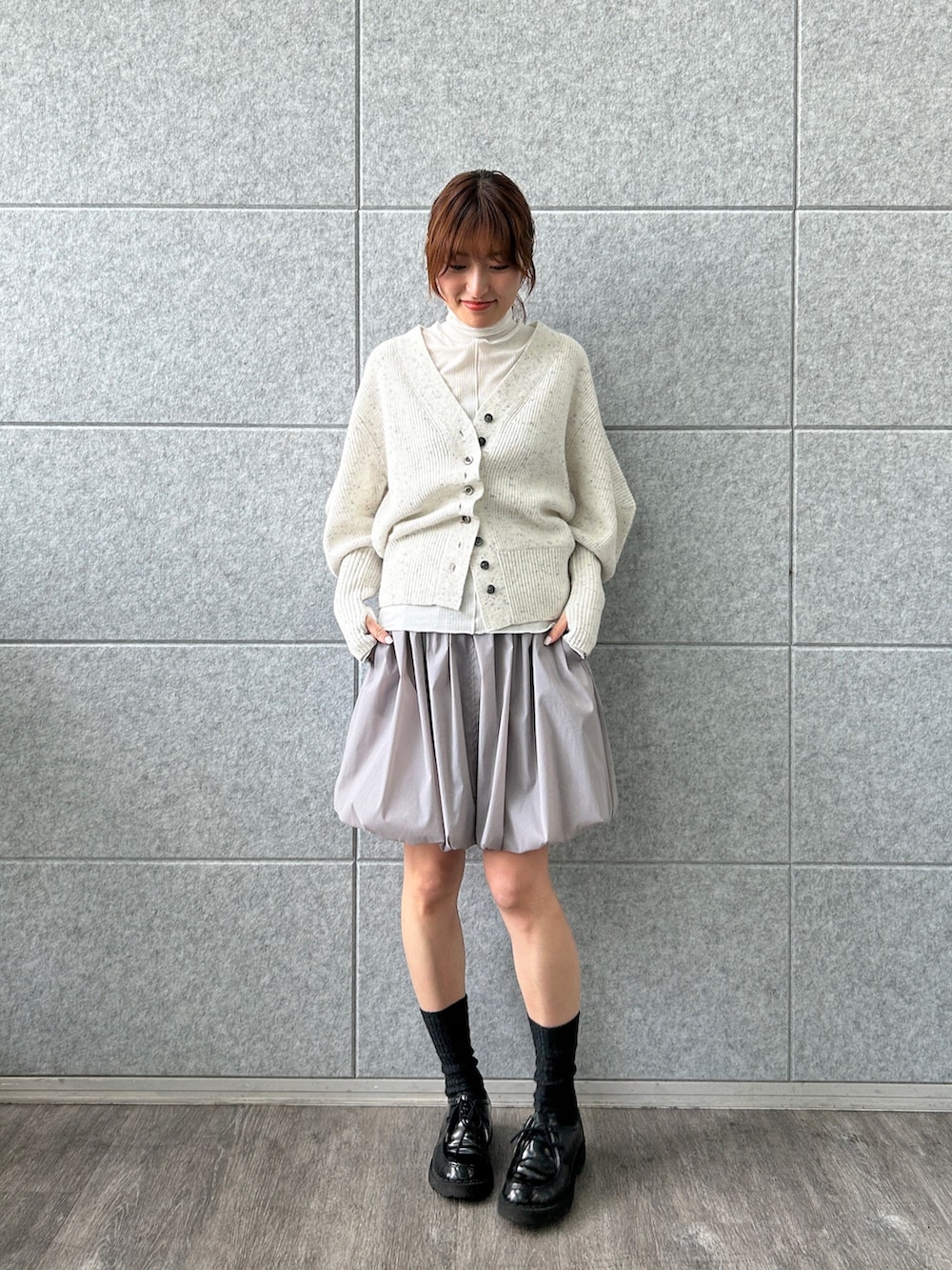 ホワイト系のカーディガン/ボレロ、グレー系のスカート、ホワイト系のTシャツ/カットソーを着用したレディースの冬コーディネートの2枚目の写真