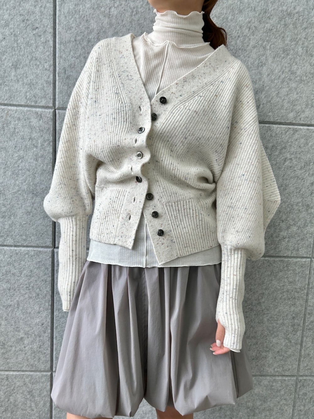 ホワイト系のカーディガン/ボレロ、グレー系のスカート、ホワイト系のTシャツ/カットソーを着用したレディースの冬コーディネートの7枚目の写真