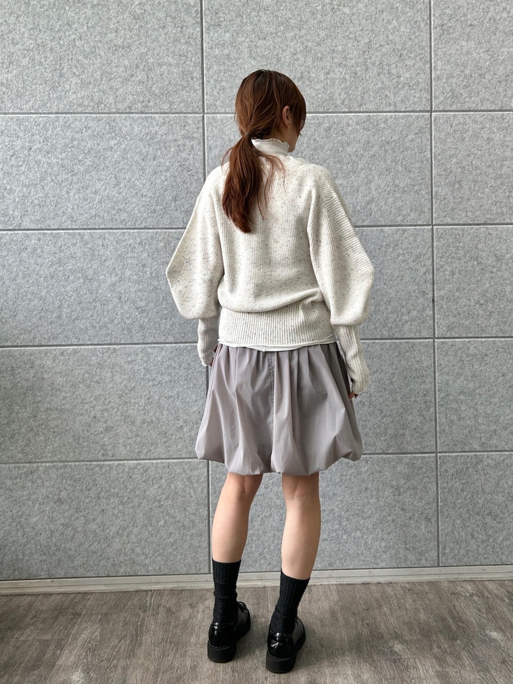 ホワイト系のカーディガン/ボレロ、グレー系のスカート、ホワイト系のTシャツ/カットソーを着用したレディースの冬コーディネートの4枚目の写真