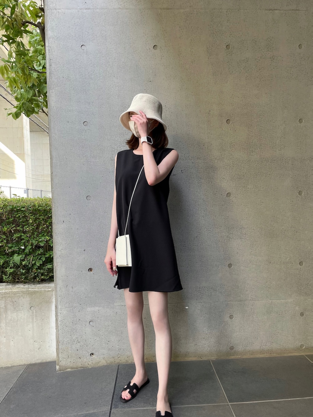 ブラック系のサンダル、ホワイト系のショルダーバッグ、ブラック系のワンピースを着用したレディースの夏コーディネートの3枚目の写真