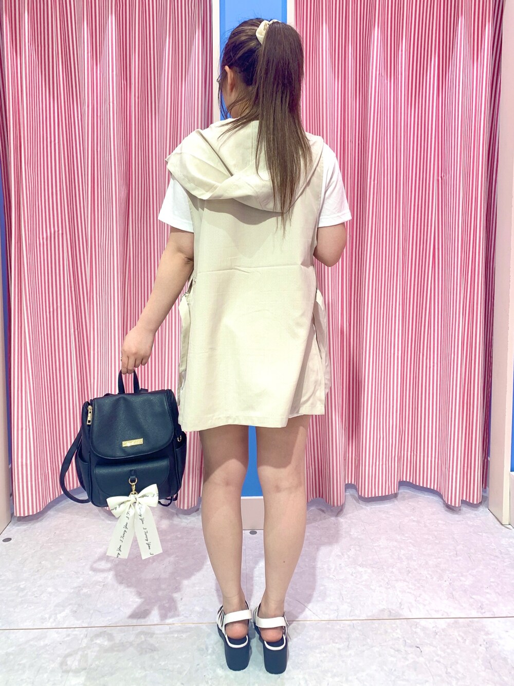 ブラック系のバックパック/リュック、ホワイト系のサンダル、ベージュ系のTシャツ/カットソーを着用したレディースの夏コーディネートの2枚目の写真