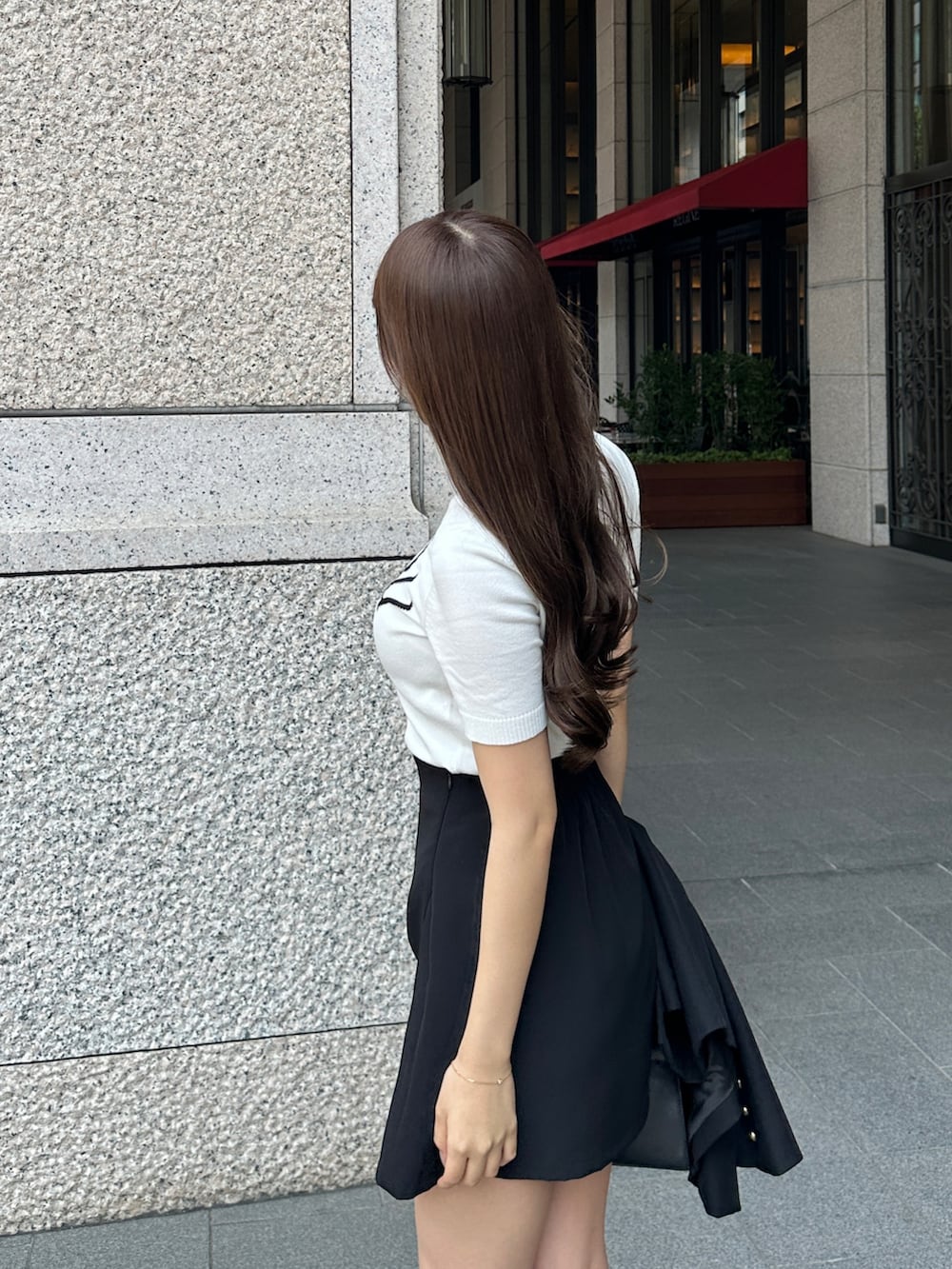 ブラック系のハンドバッグ、ブラック系のスカート、ブラック系のテーラードジャケットを着用したレディースの春コーディネートの3枚目の写真