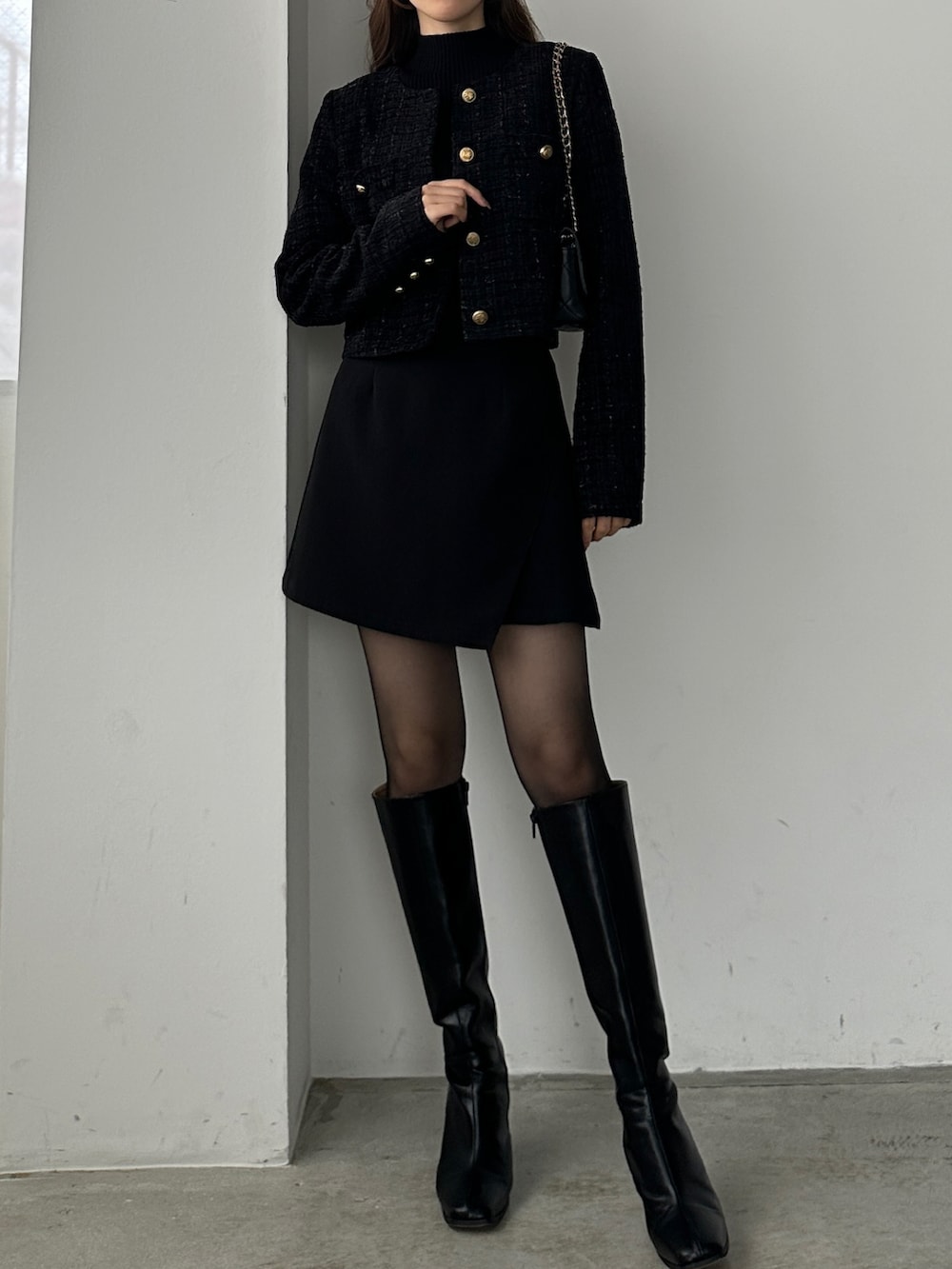 ブラック系のブーツ、ブラック系のスカート、ブラック系のノーカラージャケットを着用したレディースの秋コーディネートの2枚目の写真