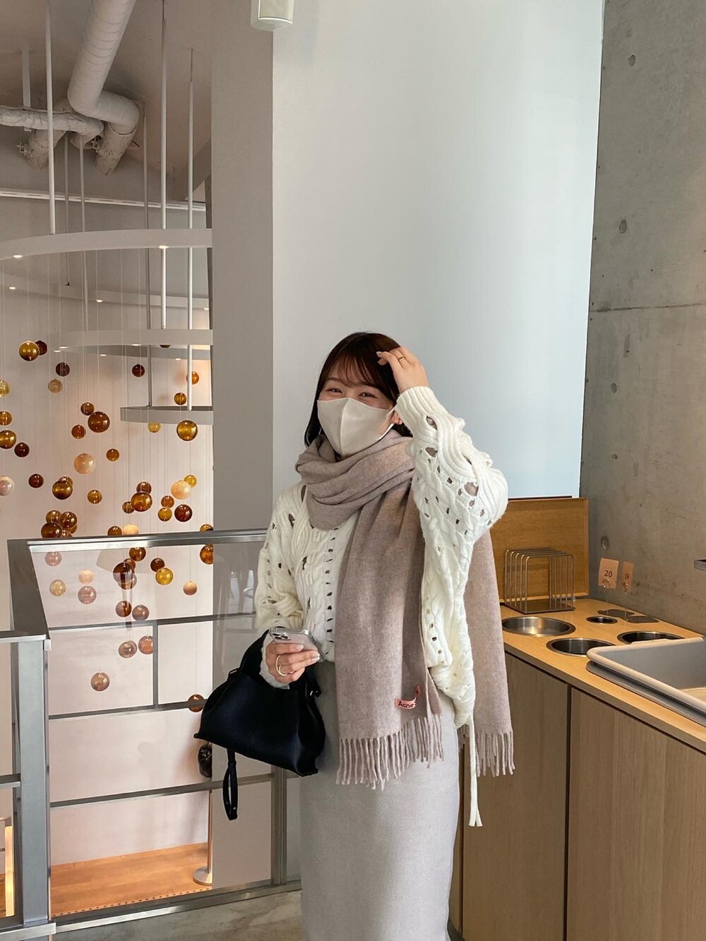 ホワイト系のニット/セーター、ブラウン系のスカート、ベージュ系のマフラーを着用したレディースの冬コーディネートの3枚目の写真