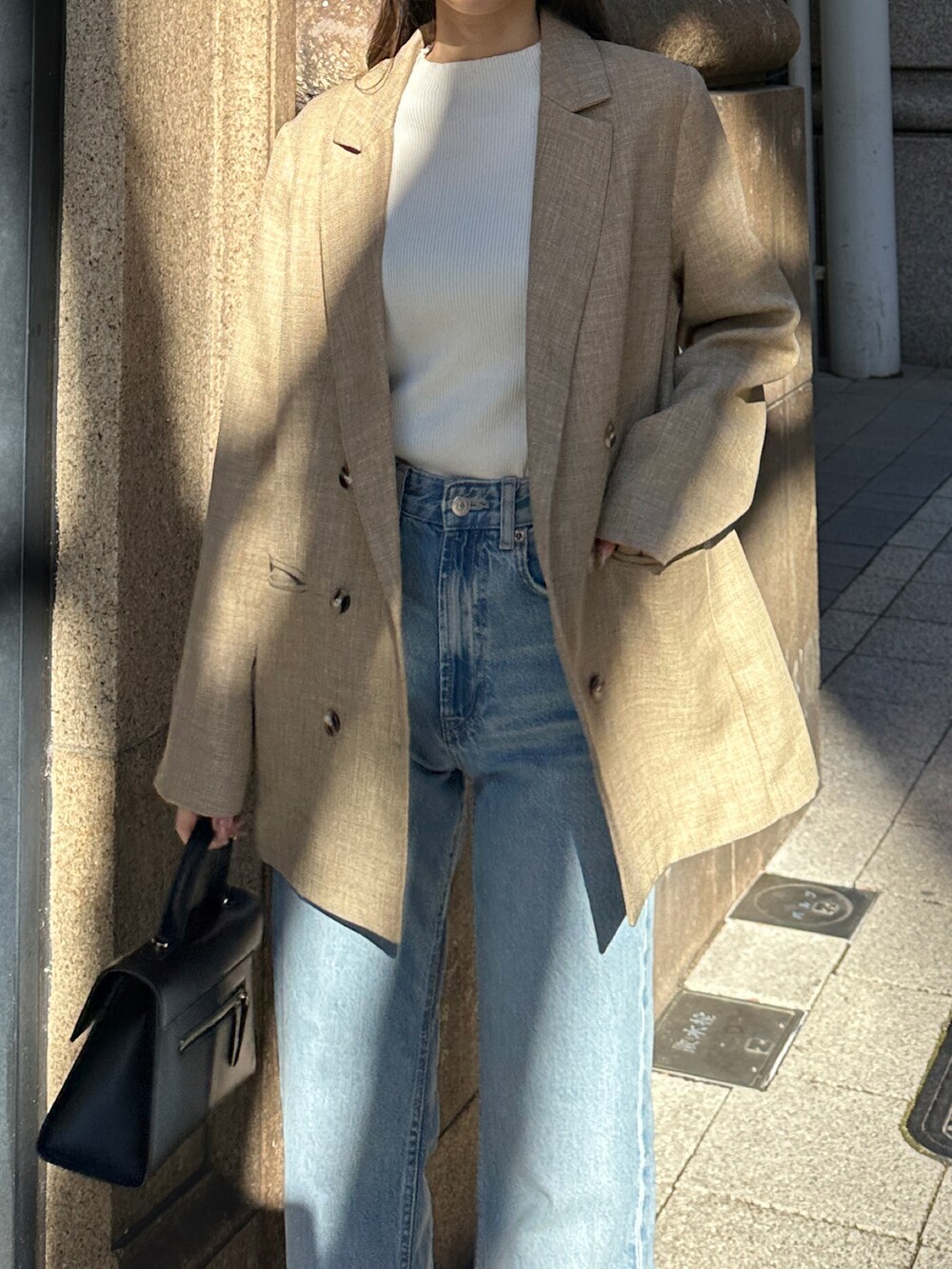 ブラック系のハンドバッグ、ブルー系のパンツを着用したレディースの冬コーディネートの4枚目の写真