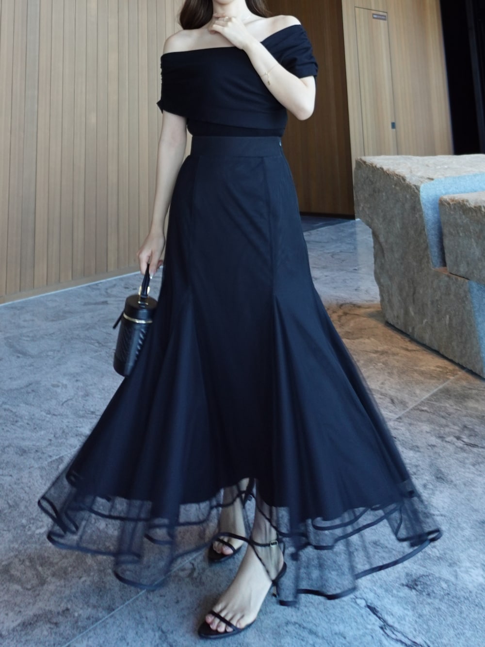 ブラック系のニット/セーター、ブラック系のスカートを着用したレディースの春コーディネートの2枚目の写真