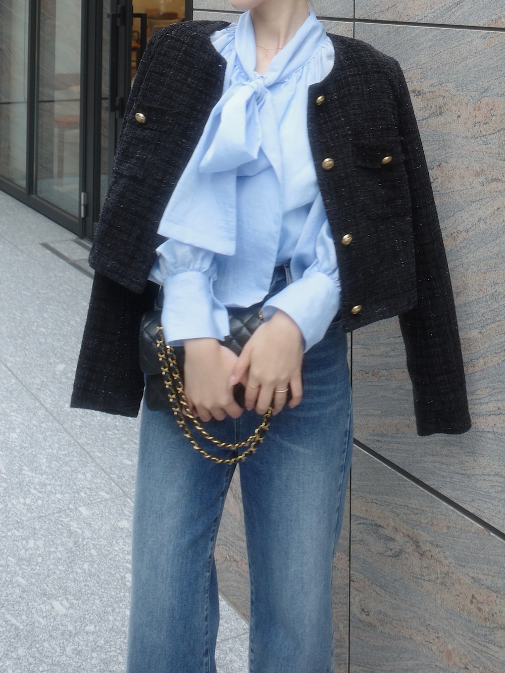 ブラック系のノーカラージャケット、ブルー系のデニムパンツを着用したレディースの春コーディネートの2枚目の写真