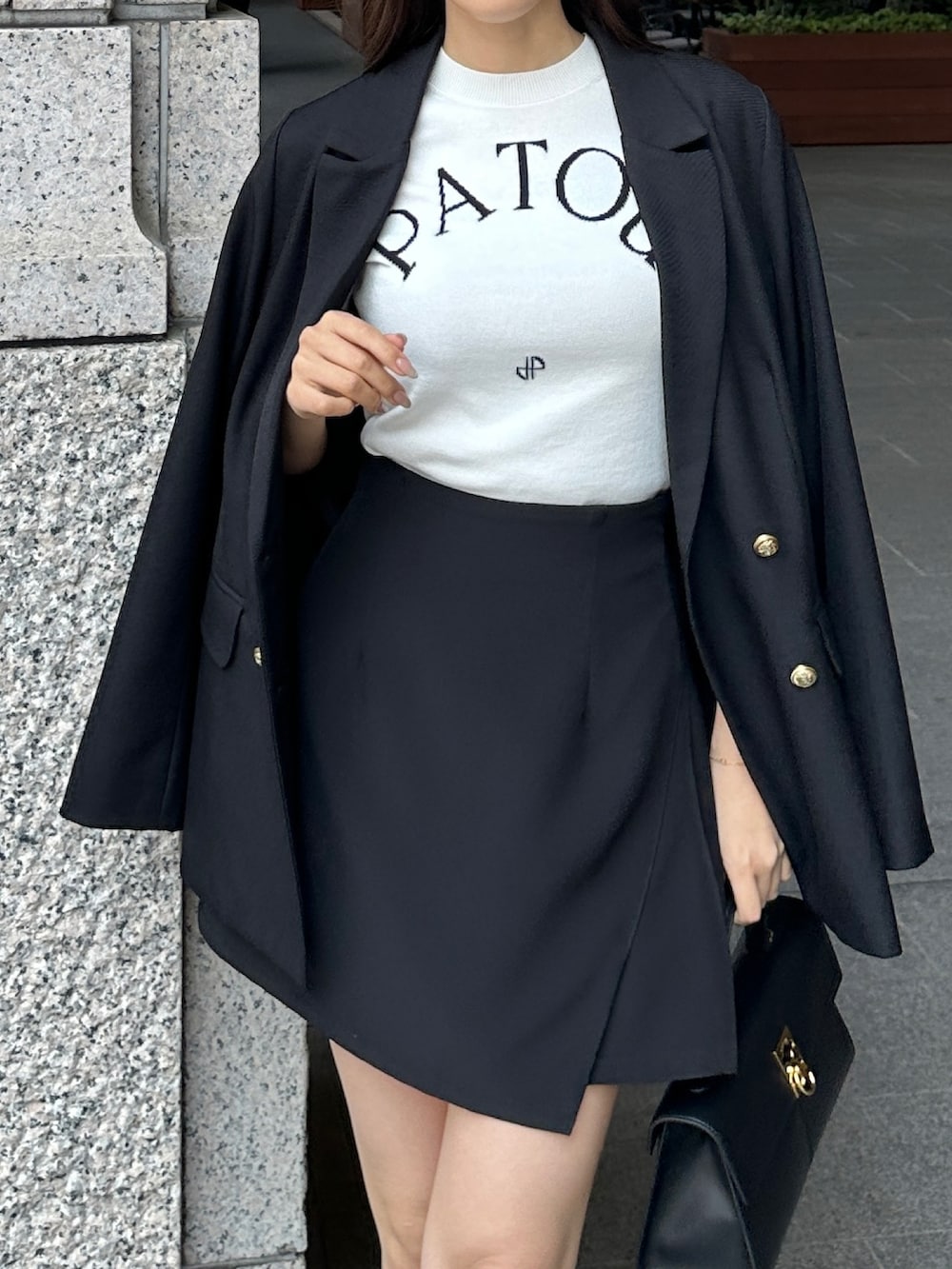 ブラック系のハンドバッグ、ブラック系のスカート、ブラック系のテーラードジャケットを着用したレディースの春コーディネートの2枚目の写真