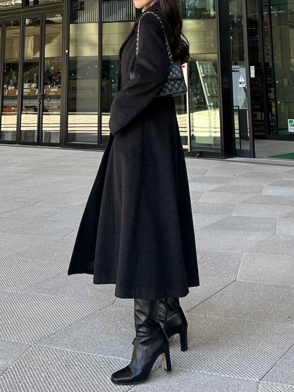 ブラック系のチェスターコート、ブラック系のスカートを着用したレディースの冬コーディネートの3枚目の写真