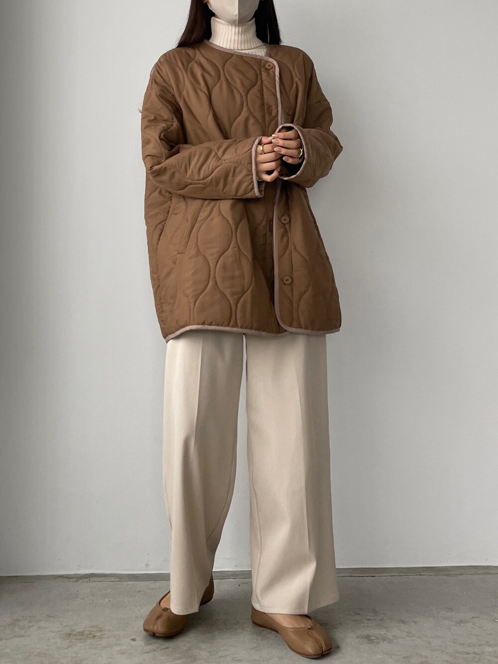 ブラウン系のダウンジャケット/コート、ホワイト系のその他パンツ、ベージュ系のニット/セーターを着用したレディースの秋コーディネートの4枚目の写真