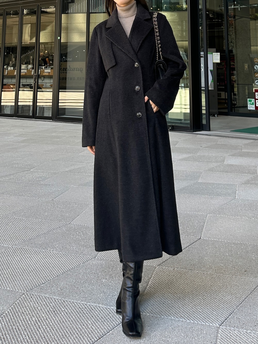 ブラック系のチェスターコート、ブラック系のスカートを着用したレディースの冬コーディネートの2枚目の写真